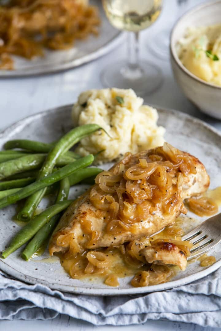 Baked Chicken and Shallots on grey plate with green beans and mashed potatoes