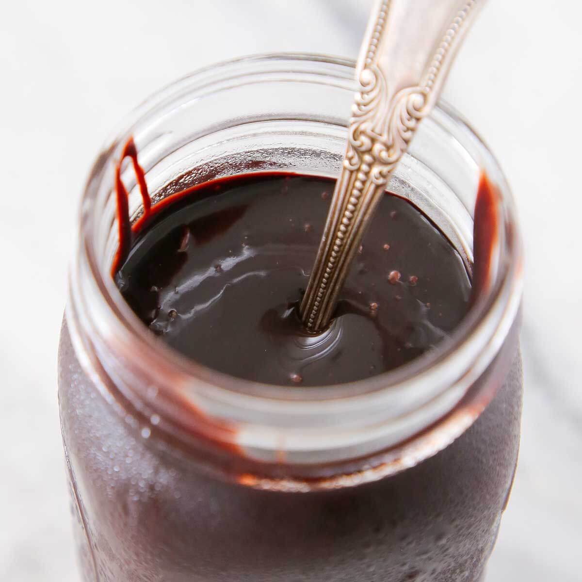 chocolate fudge sauce in jar on marble. 