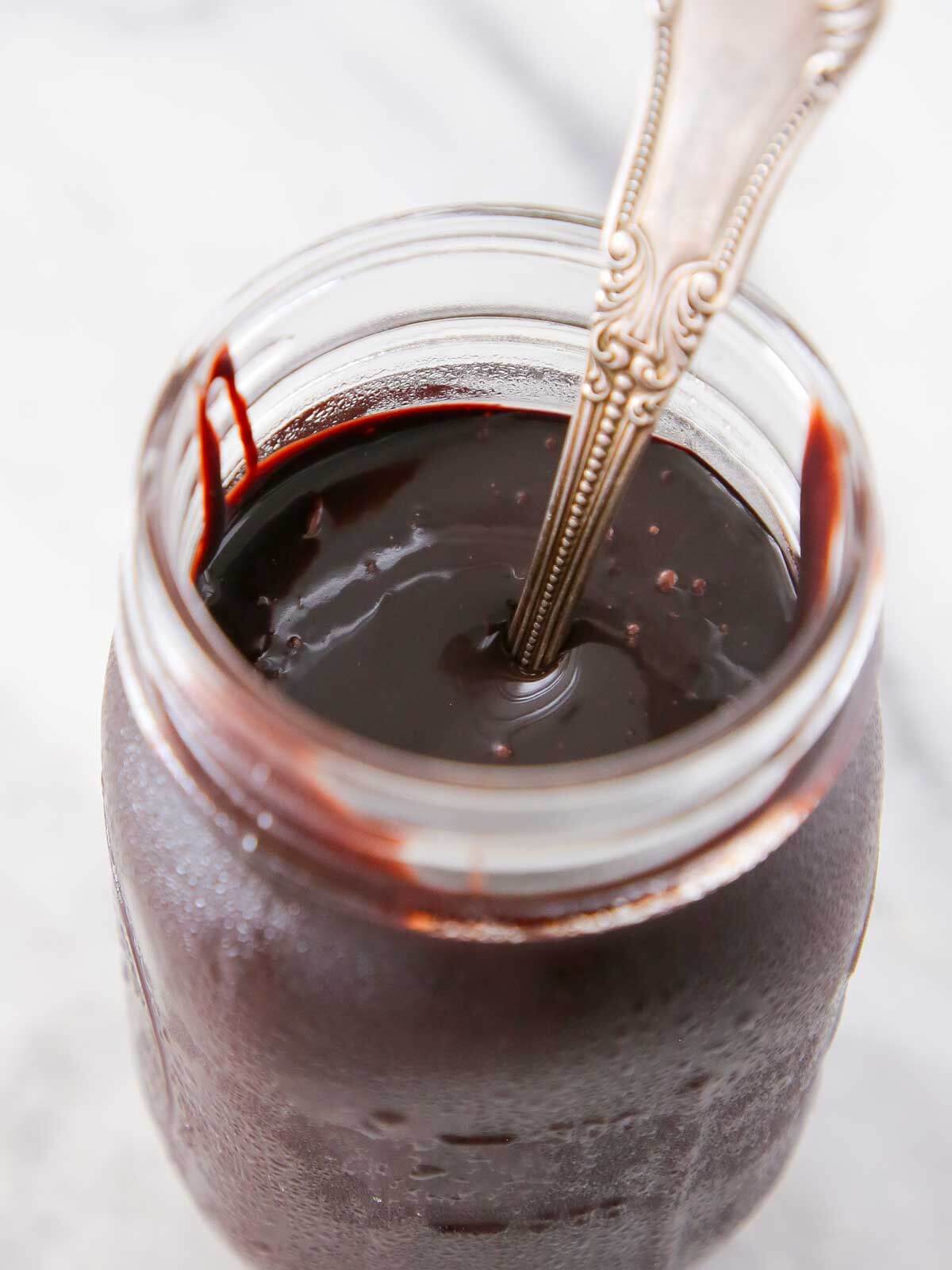 chocolate fudge sauce in jar with spoon.