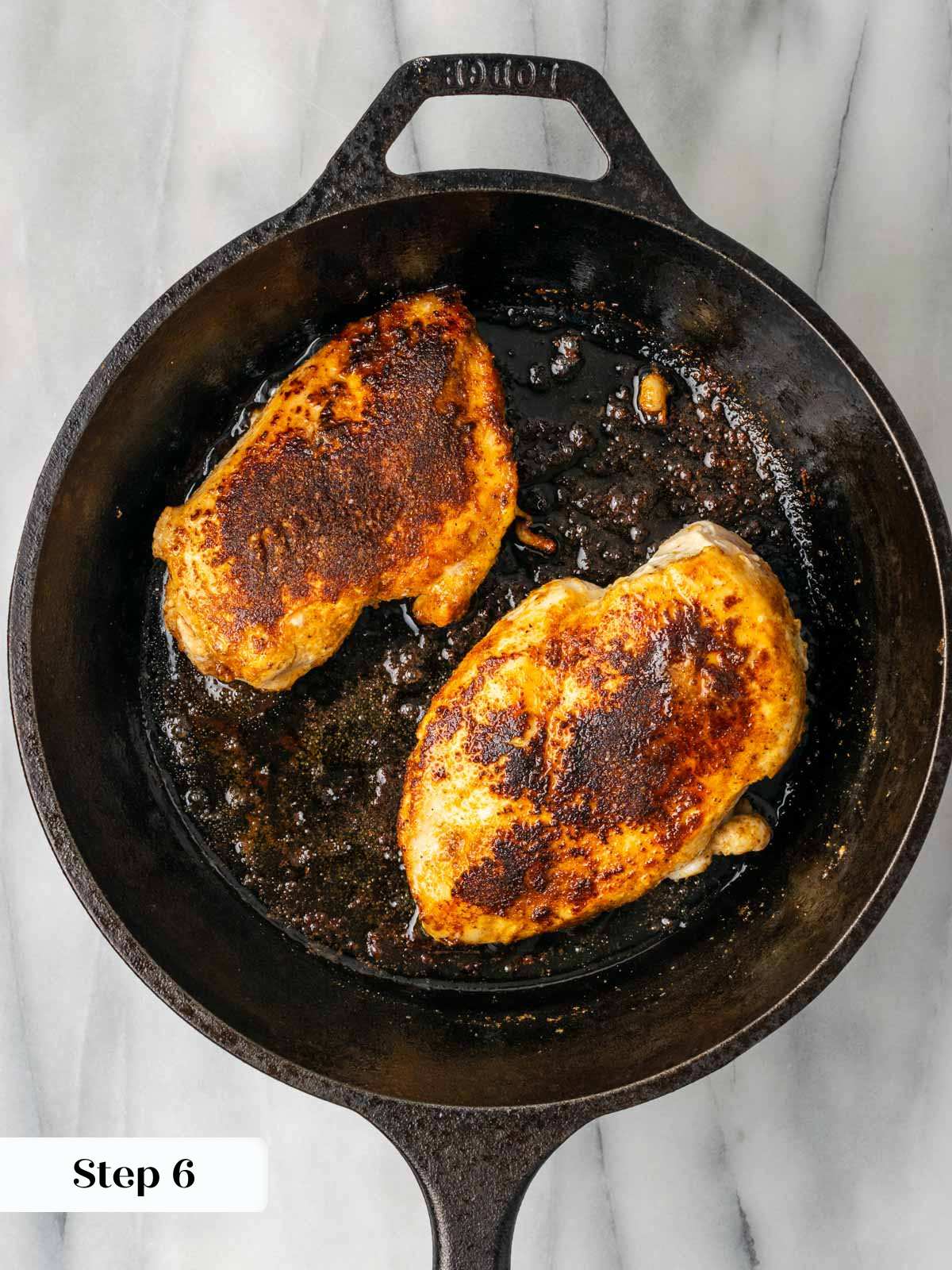 searing chicken breasts in black cast iron skillet.