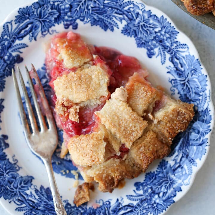 Strawberry Rhubarb Pie in almond lattice crust slice on blue plate
