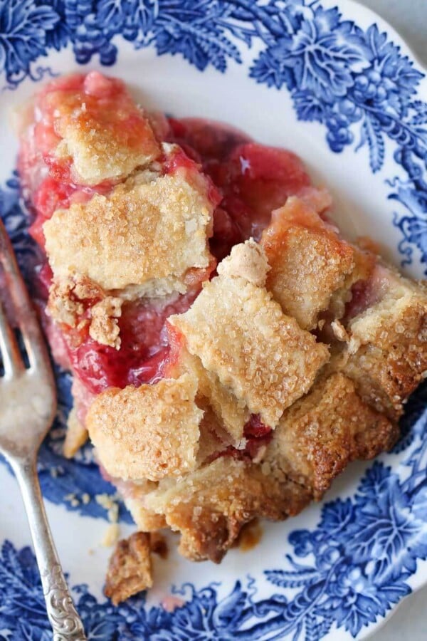 slice of strawberry rhubarb pie on blue plate.