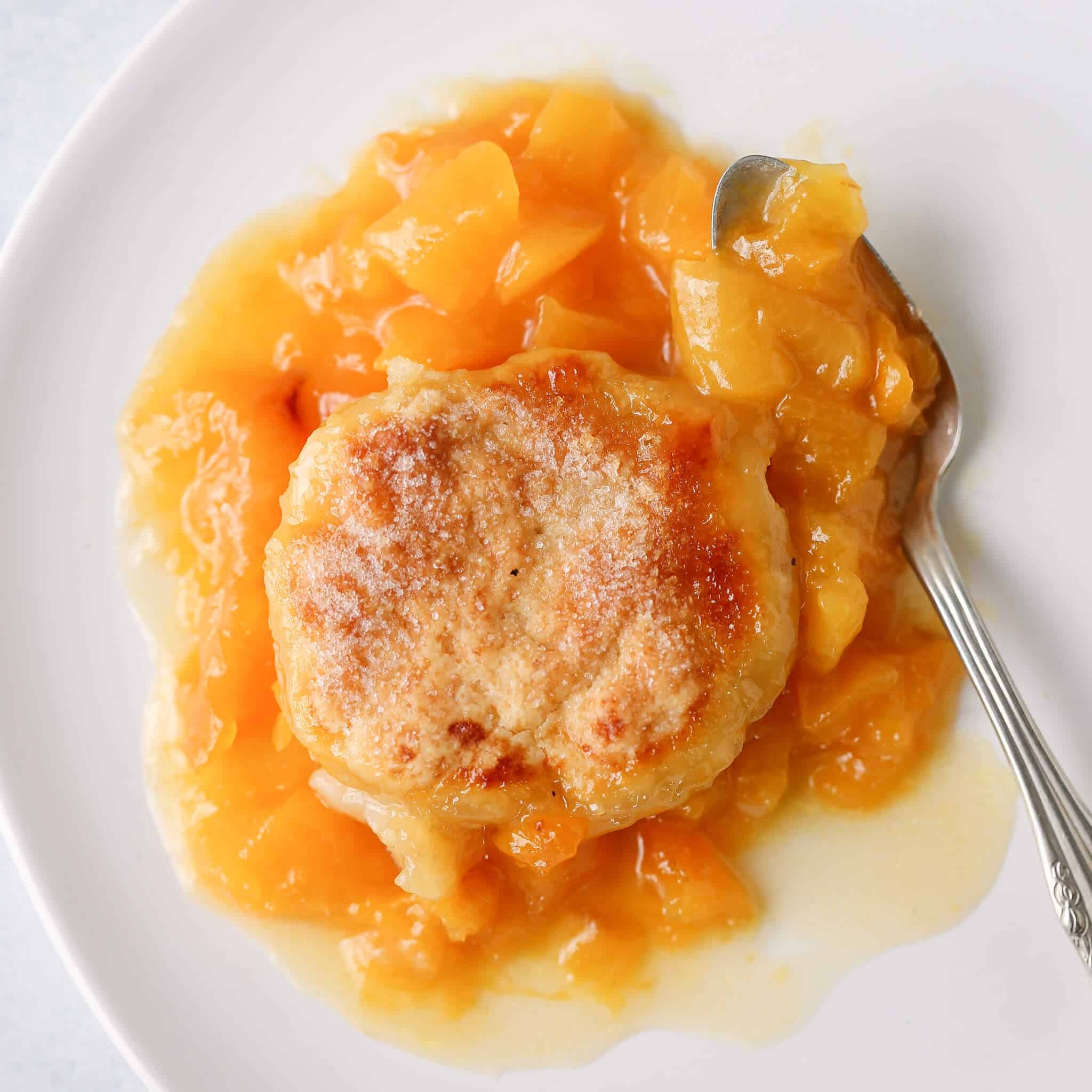 Old Fashioned Peach Cobbler on white plate with vintage spoon