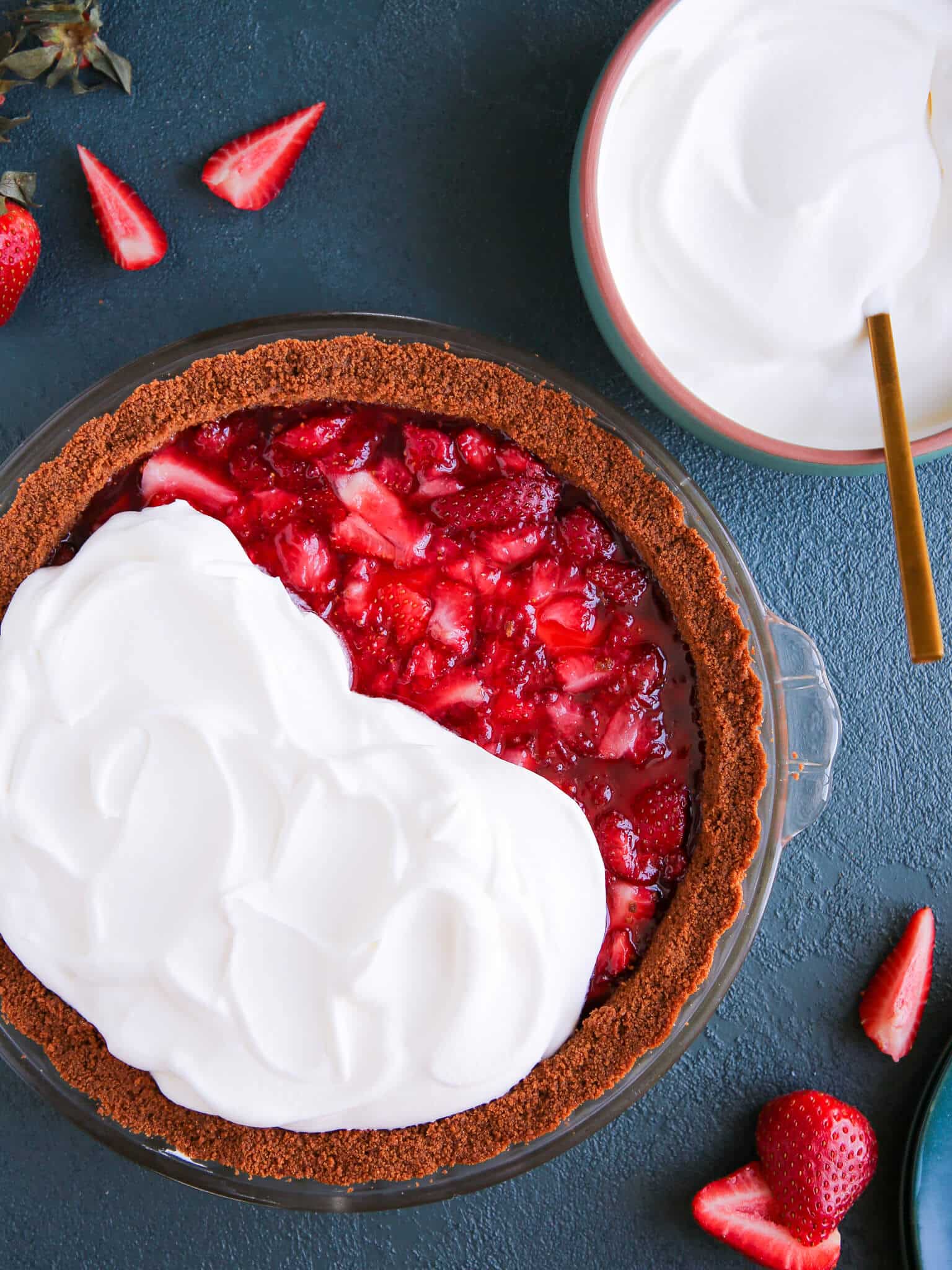 Strawberry Triumph Pie unsliced whipped cream on teal surface.