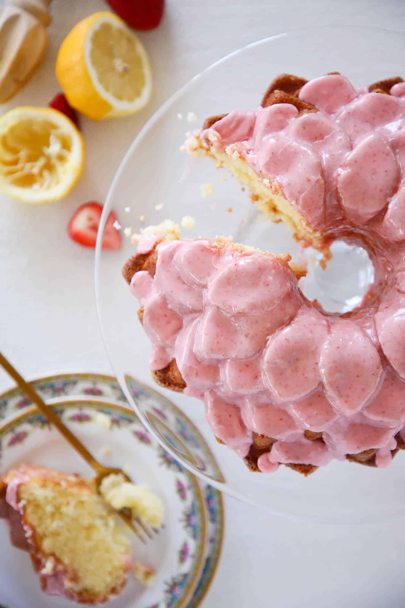 Lemon Pound Cake Strawberry Icing sliced cake on glass pedestal white background Valentine's Day Desserts.