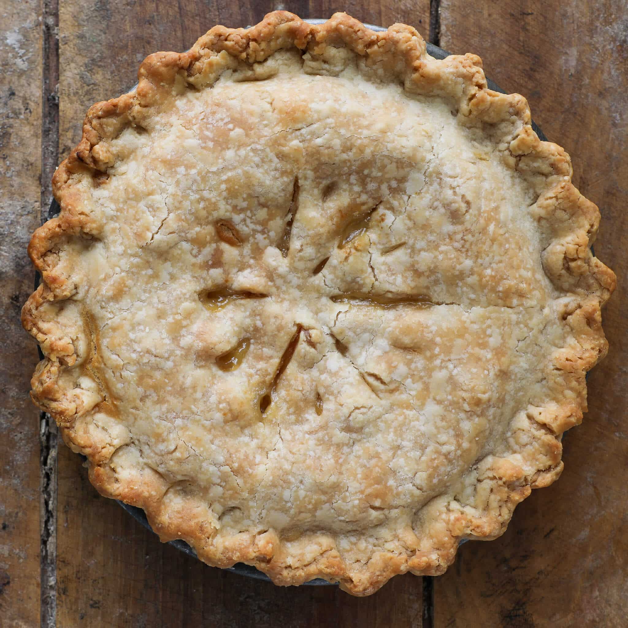 Old Fashioned Peach Pie unsliced baked on wooden surface.