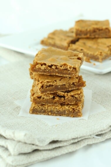 A stack of butterscotch brownies on a beige cloth.