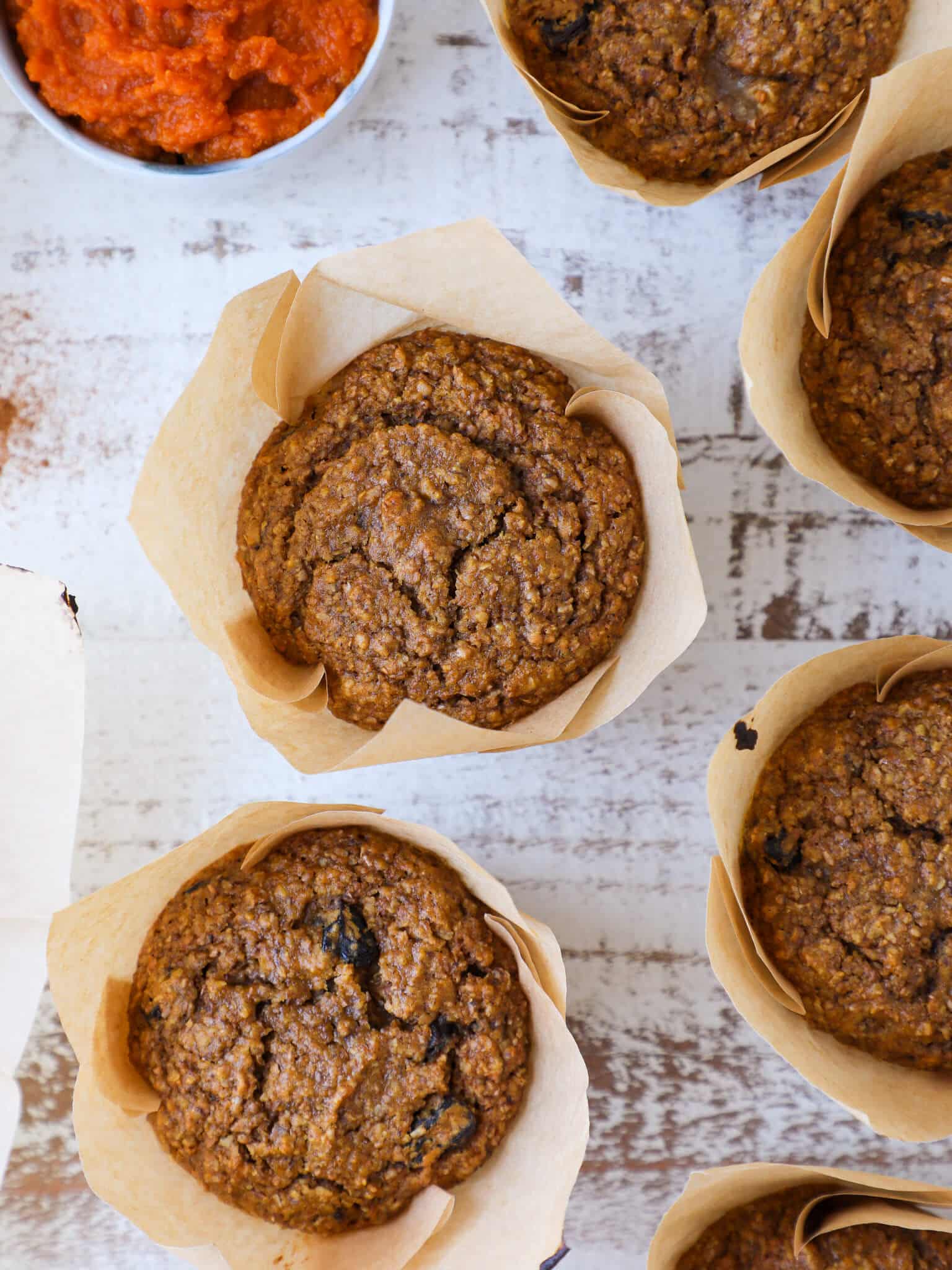 baked pumpkin bran muffins on white washed board. 