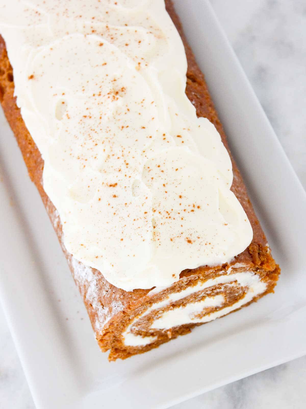 unsliced pumpkin roll with cream cheese frosting on top.