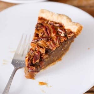 pecan pie slice on white plate with vintage fork.