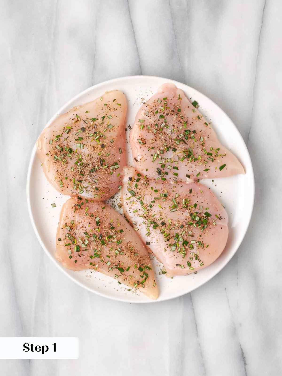 seasoned raw chicken breasts on white plate.