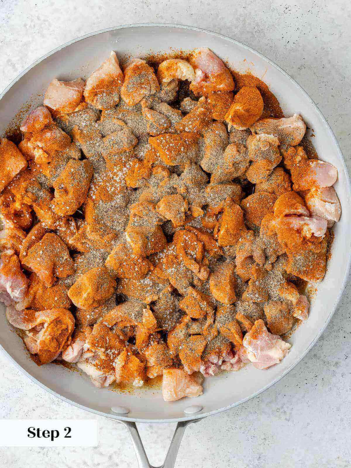 Chicken with spices in pan.