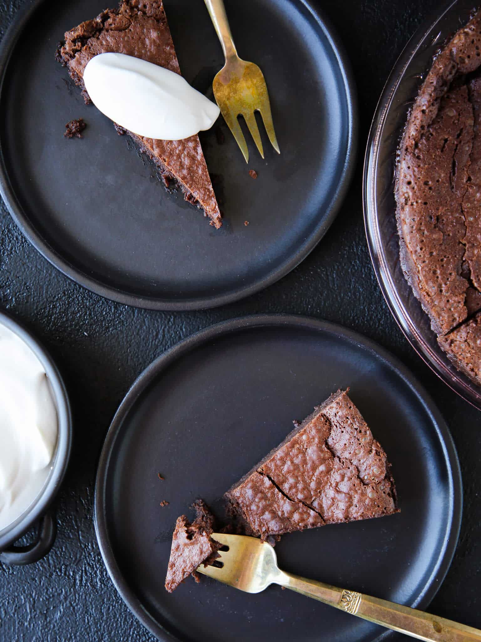 Flourless Chocolate Decadence Cake slices on black plates with whipped cream for Valentine's Day Desserts.