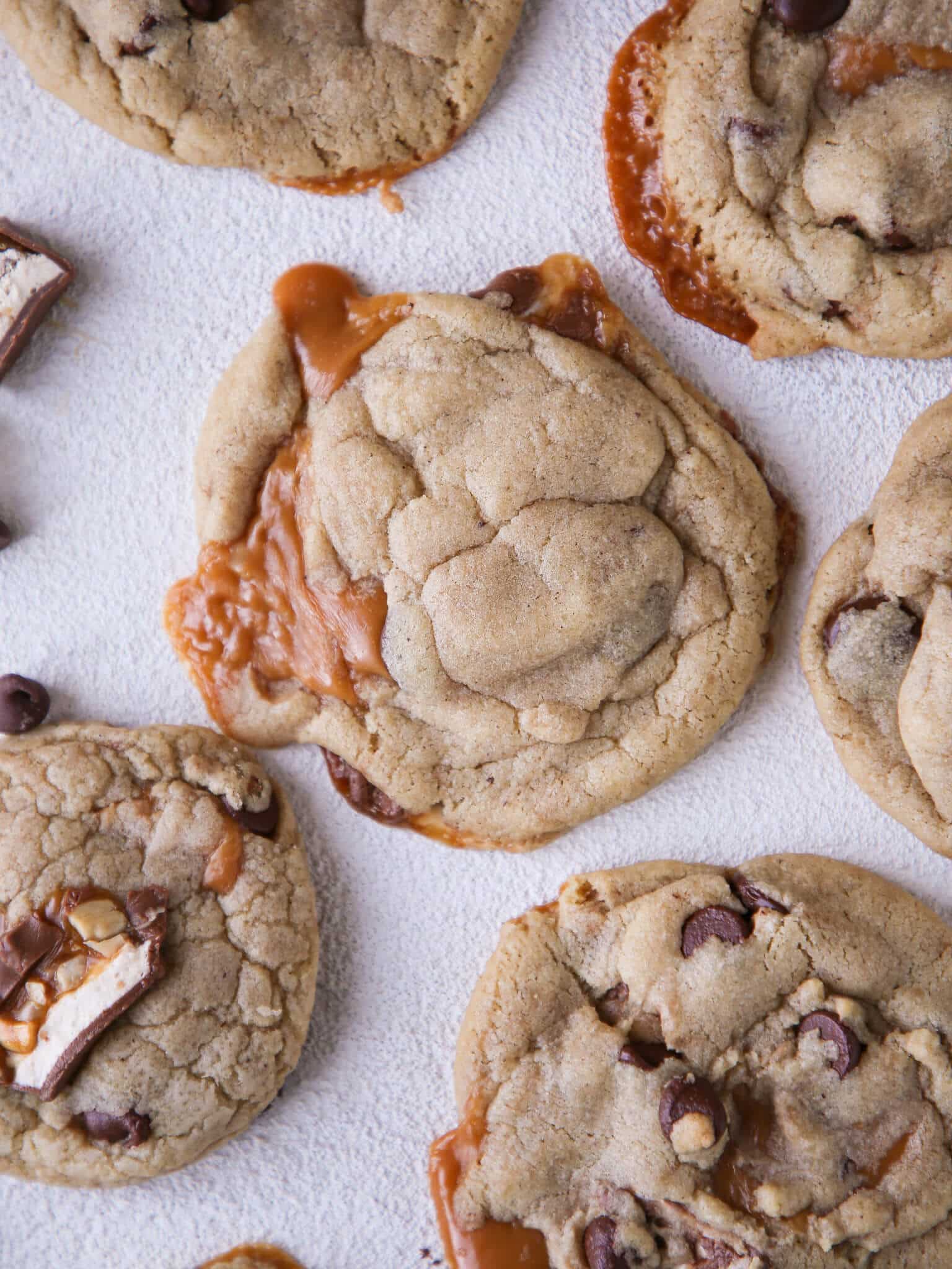 Caramel Stuffed Brown Butter Snickers Chocolate Chip Cookies with caramel spilling out