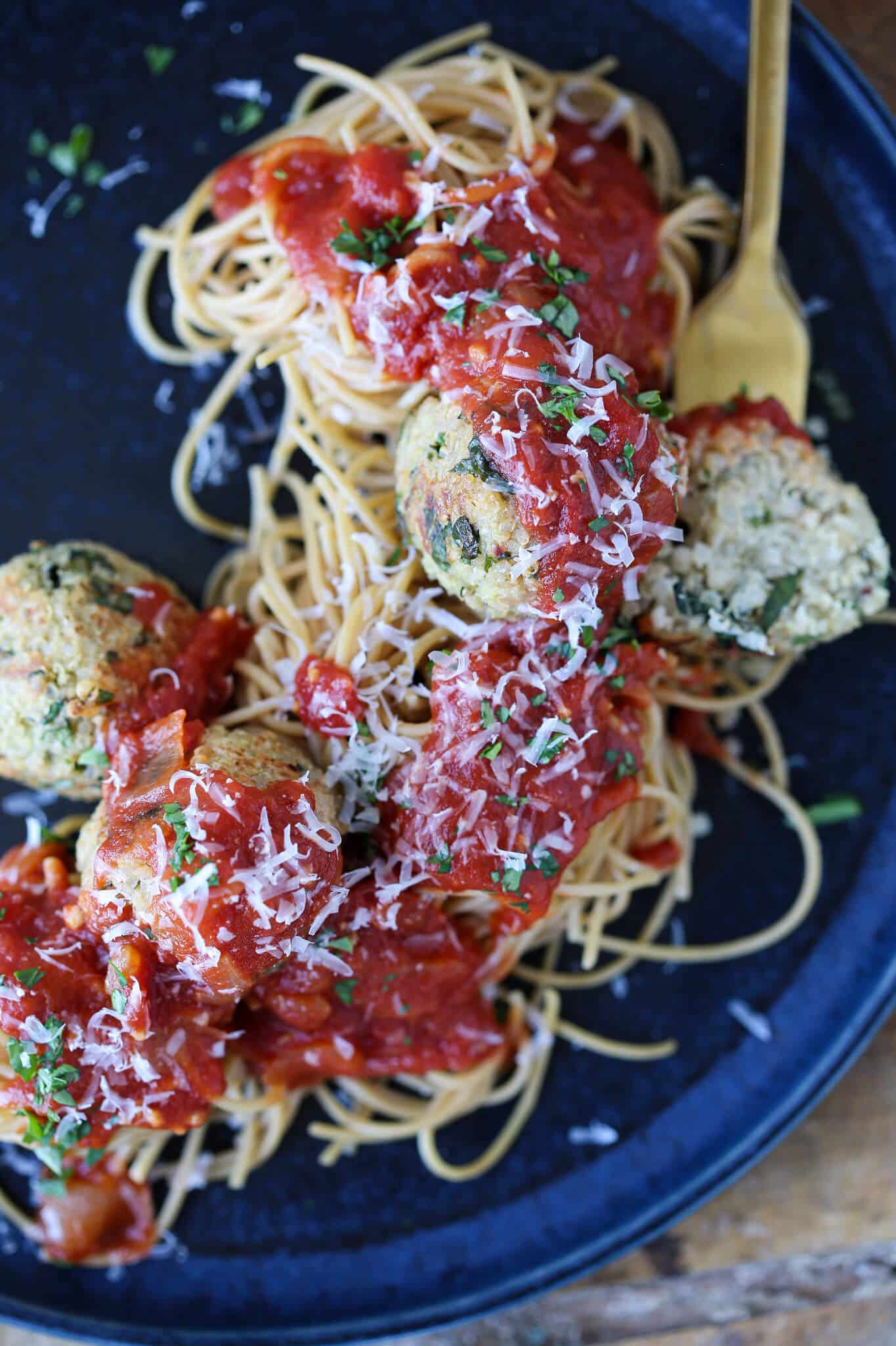 Quinoa Vegetarian Meatballs in sauce on pasta on blue plate