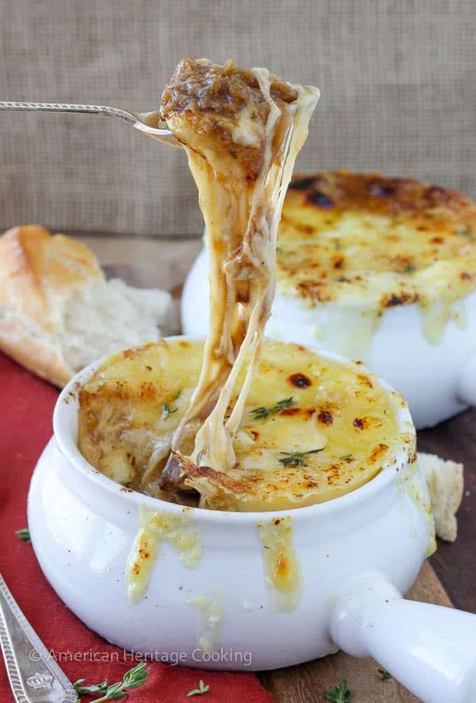 French onion soup in a white handled bowl.