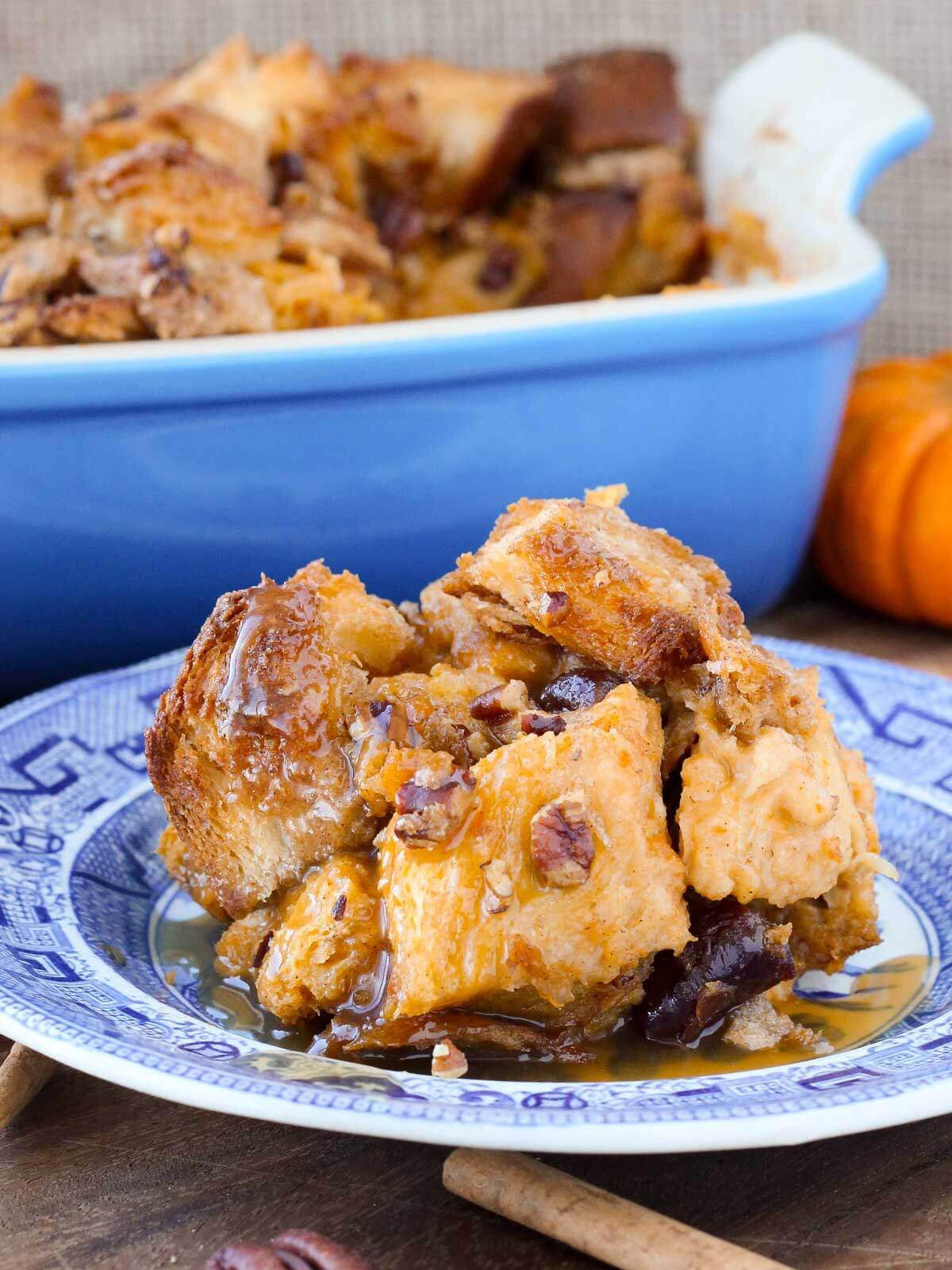pumpkin bread pudding blue plate with sauce wood background.