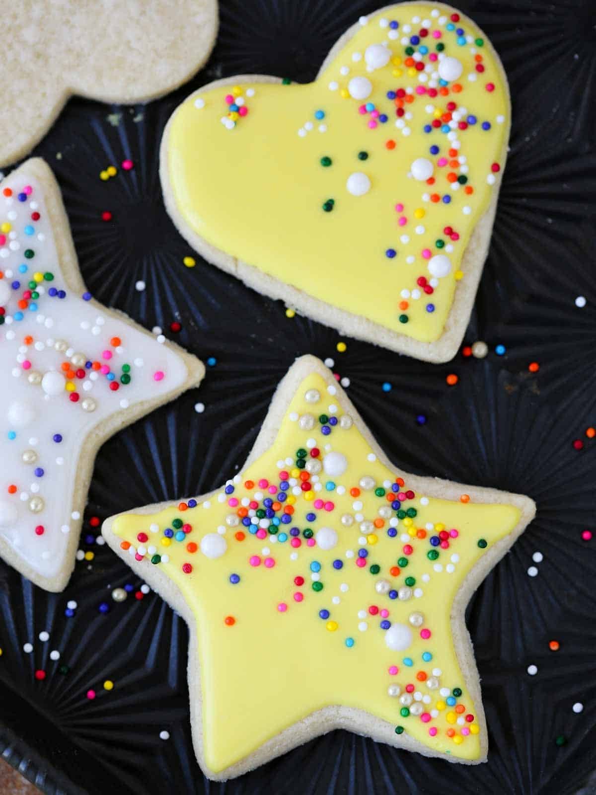 yellow star and heart cookies on black tray.
