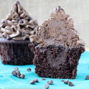 Two chocolate cupcakes with spare chocolate chips on the counter.