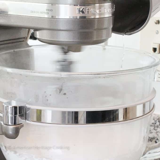 sugar syrup pouring into whipping egg whites in stand mixer. 