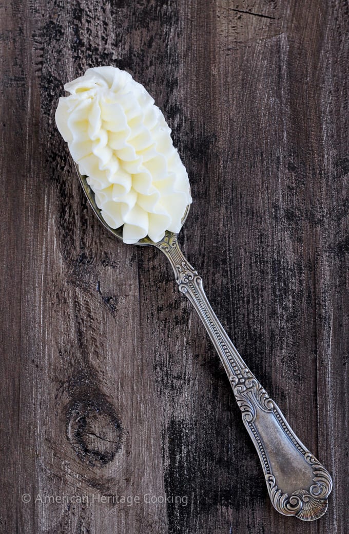 italian meringue buttercream piped on spoon on wood surface.