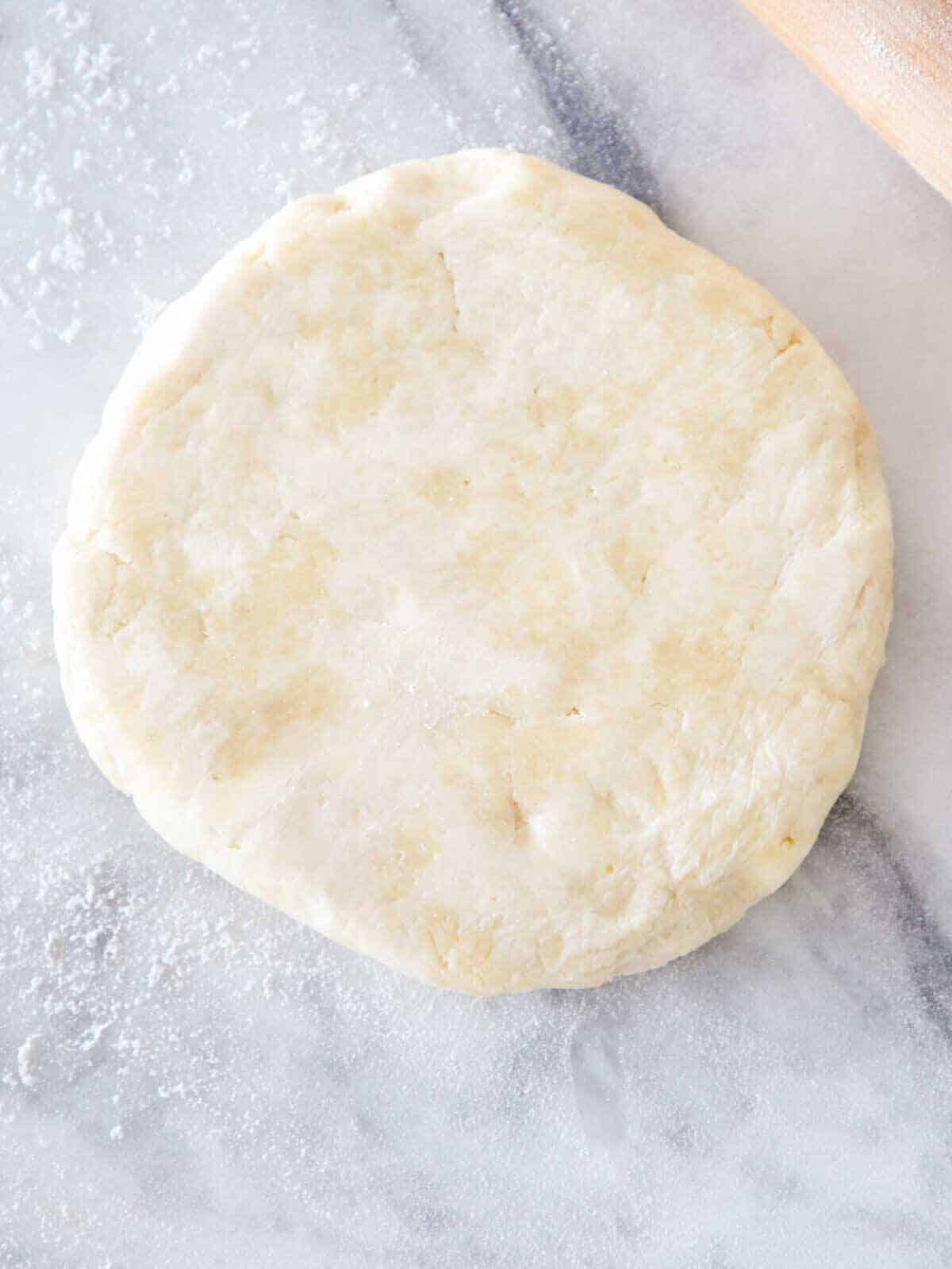 pie dough unrolled on floured marble surface.