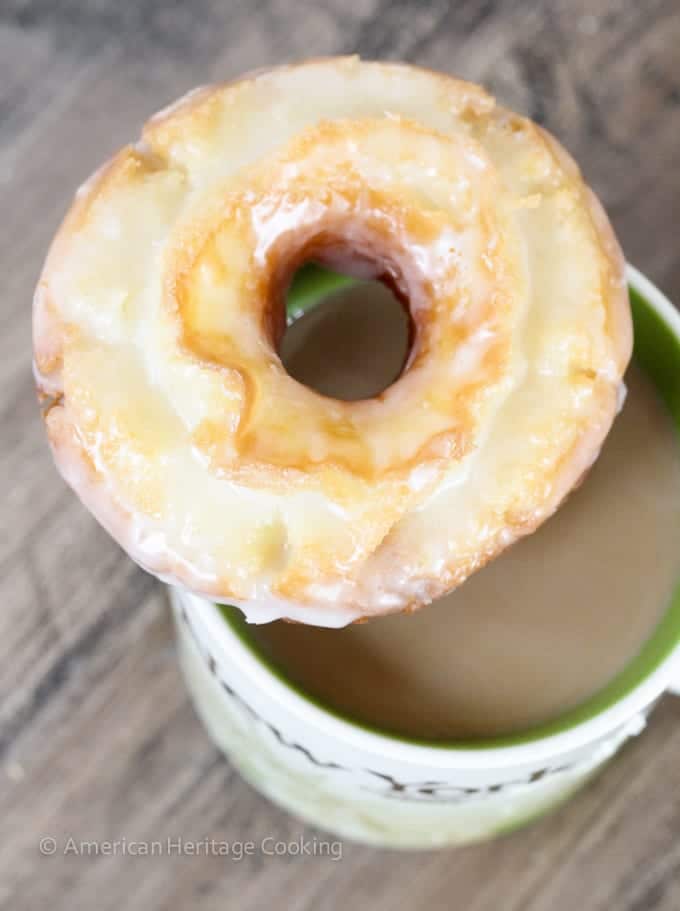 Sour cream donut resting on coffee mug overhead