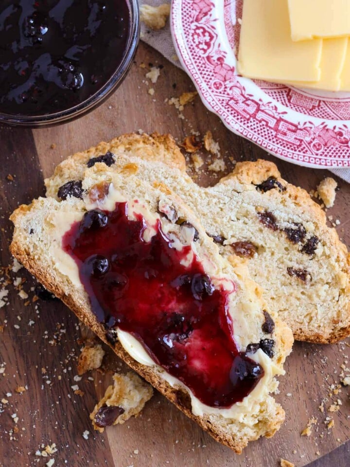 two irish soda bread slices on wooden board with jam.