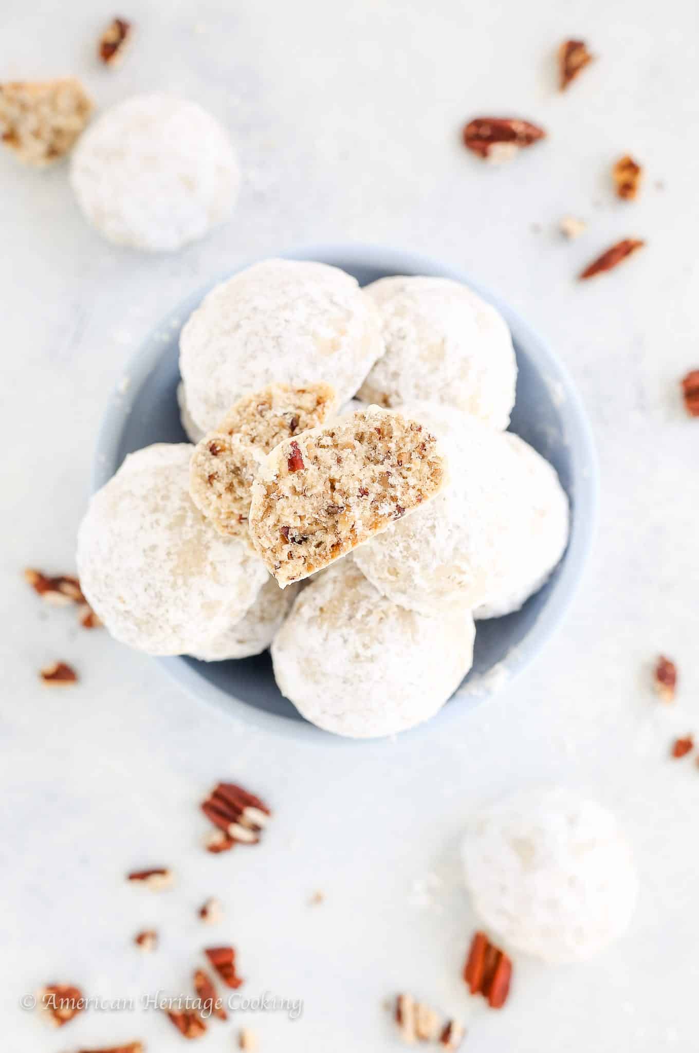 Mexican wedding cookies on white countertop with pecans.