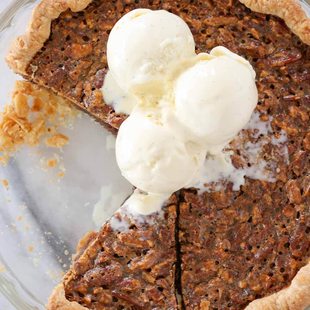 pecan pie sliced in dish with scoops of vanilla bean ice cream on top. 