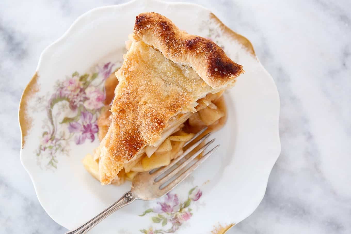 A slice of apple pie with a golden top crust.