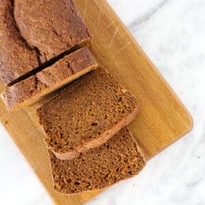 pumpkin bread slices wooden board on marble counter.