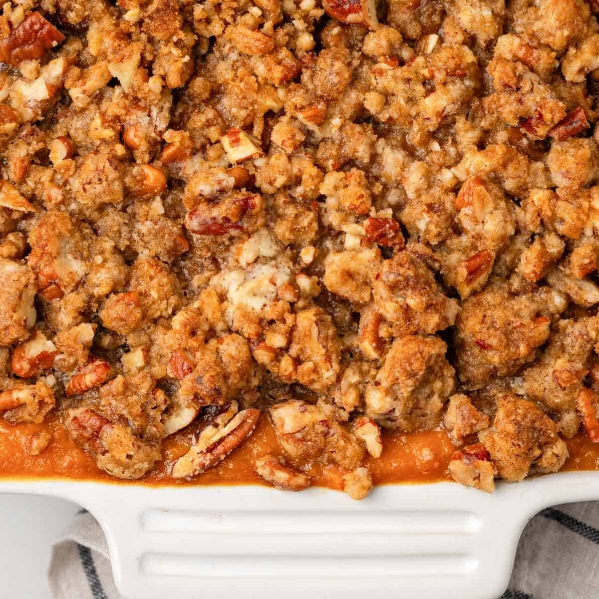 baked sweet potato casserole in white serving dish.