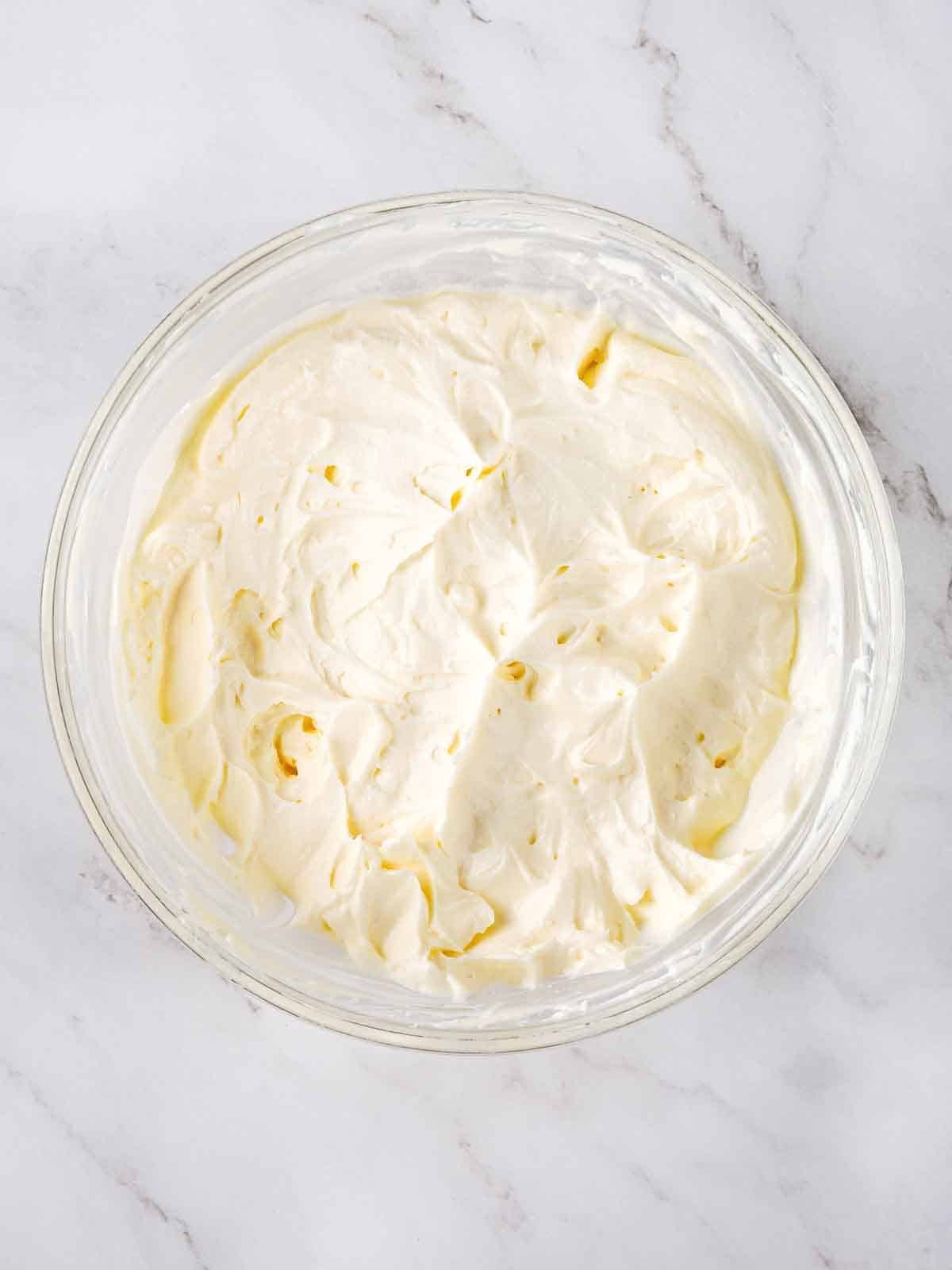 fluffy cream cheese frosting in clear bowl.
