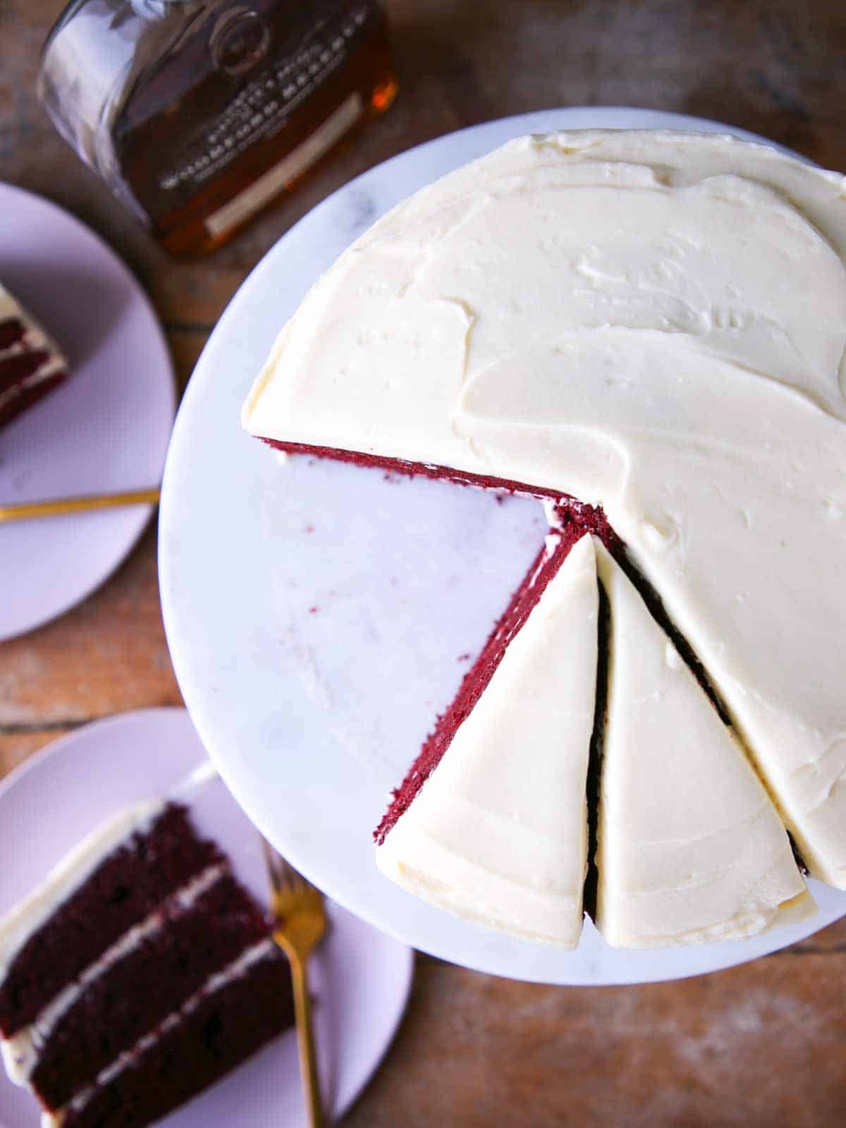red velvet cake sliced with bourbon cream cheese buttercream cake slices on pink plates.
