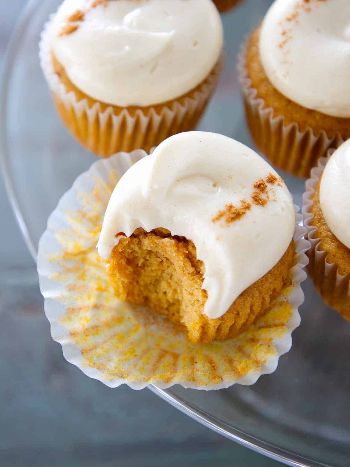 spiced cream cheese buttercream on pumpkin cupcakes on cake stand.