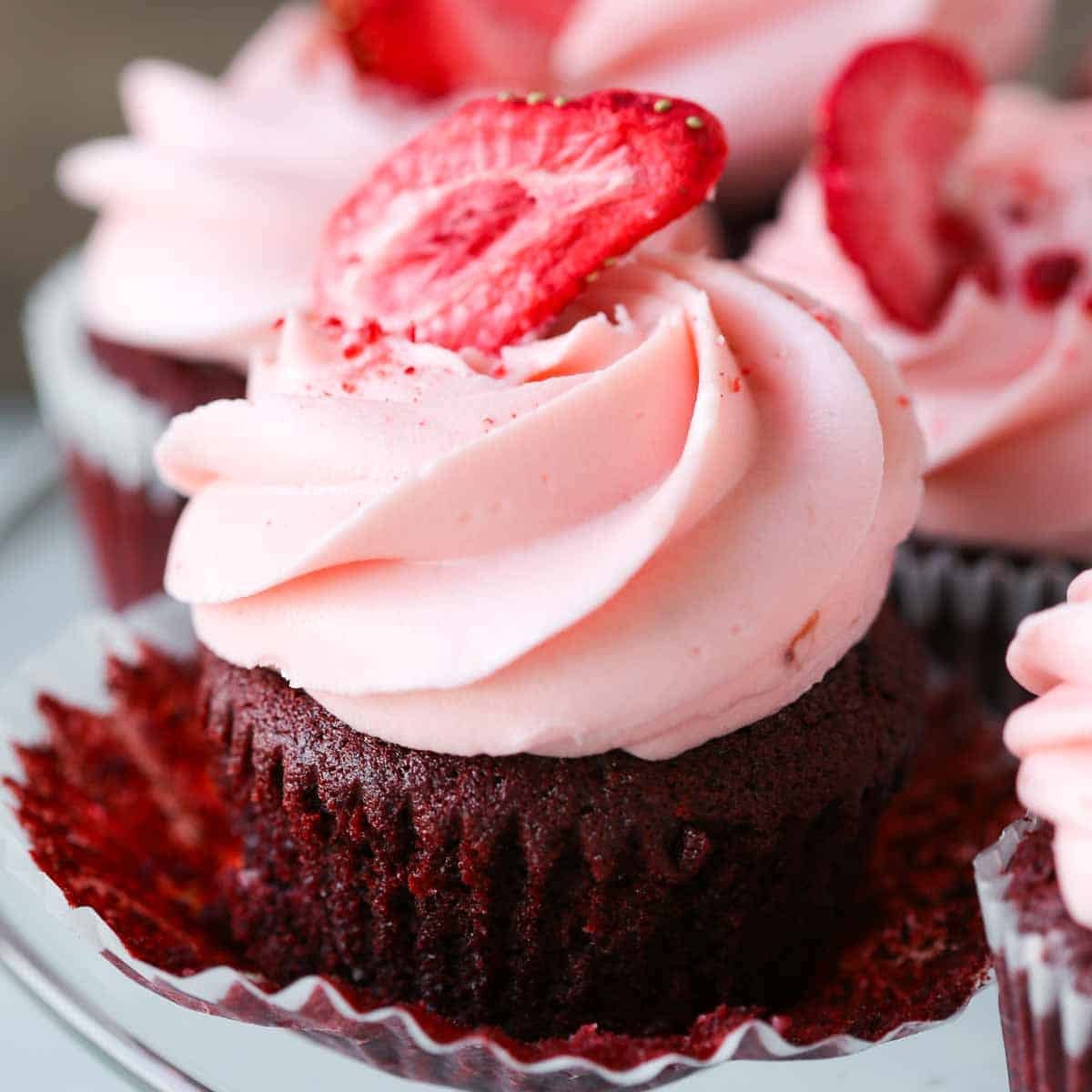 strawberry cream cheese buttercream on red velvet cupcake piped with strawberry on top.