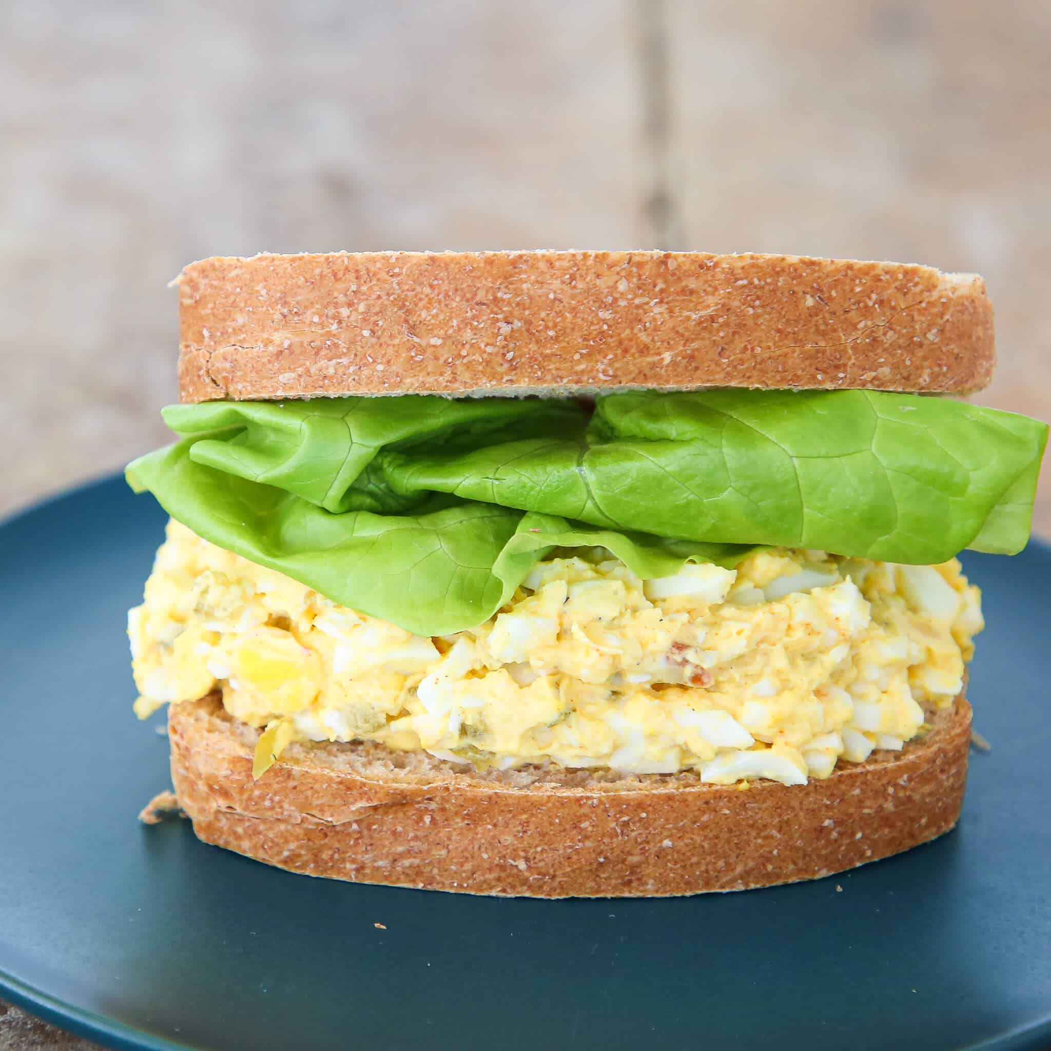 Two egg salad sandwiches assembled with lettuce and whole wheat bread.