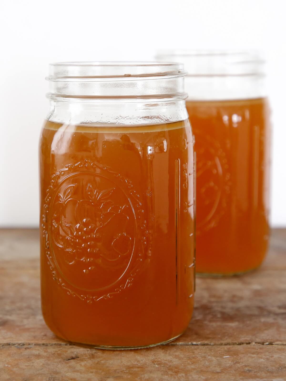 Two mason jars filled with chicken broth.