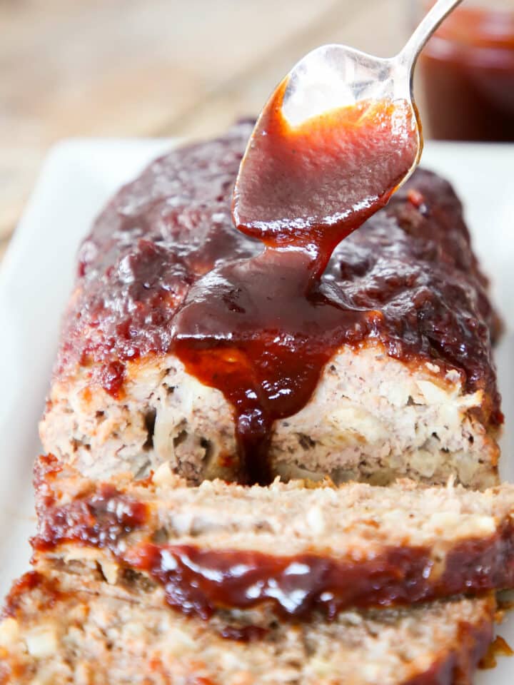 Sliced meatloaf with brown sugar sauce pouring over the top.