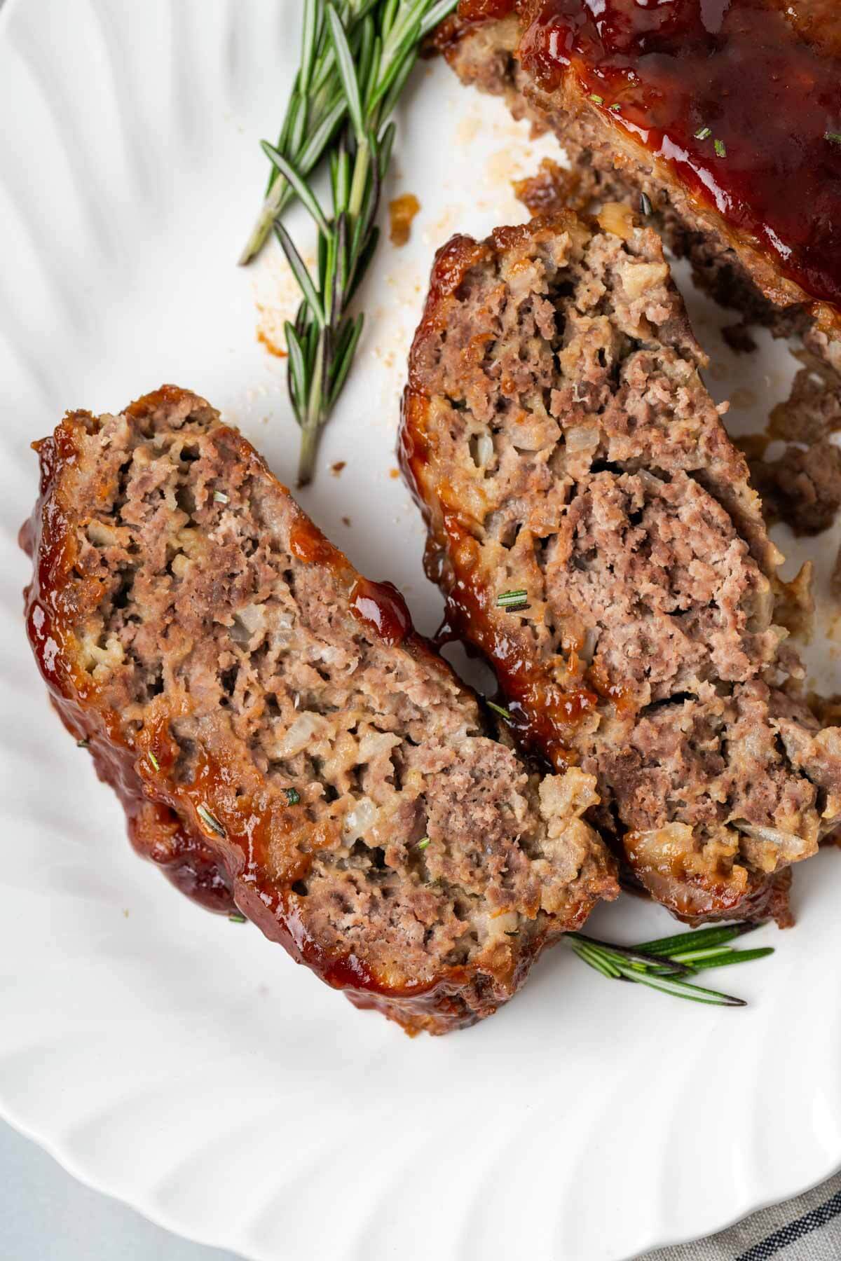 brown sugar meatloaf sliced on plate with rosemary.