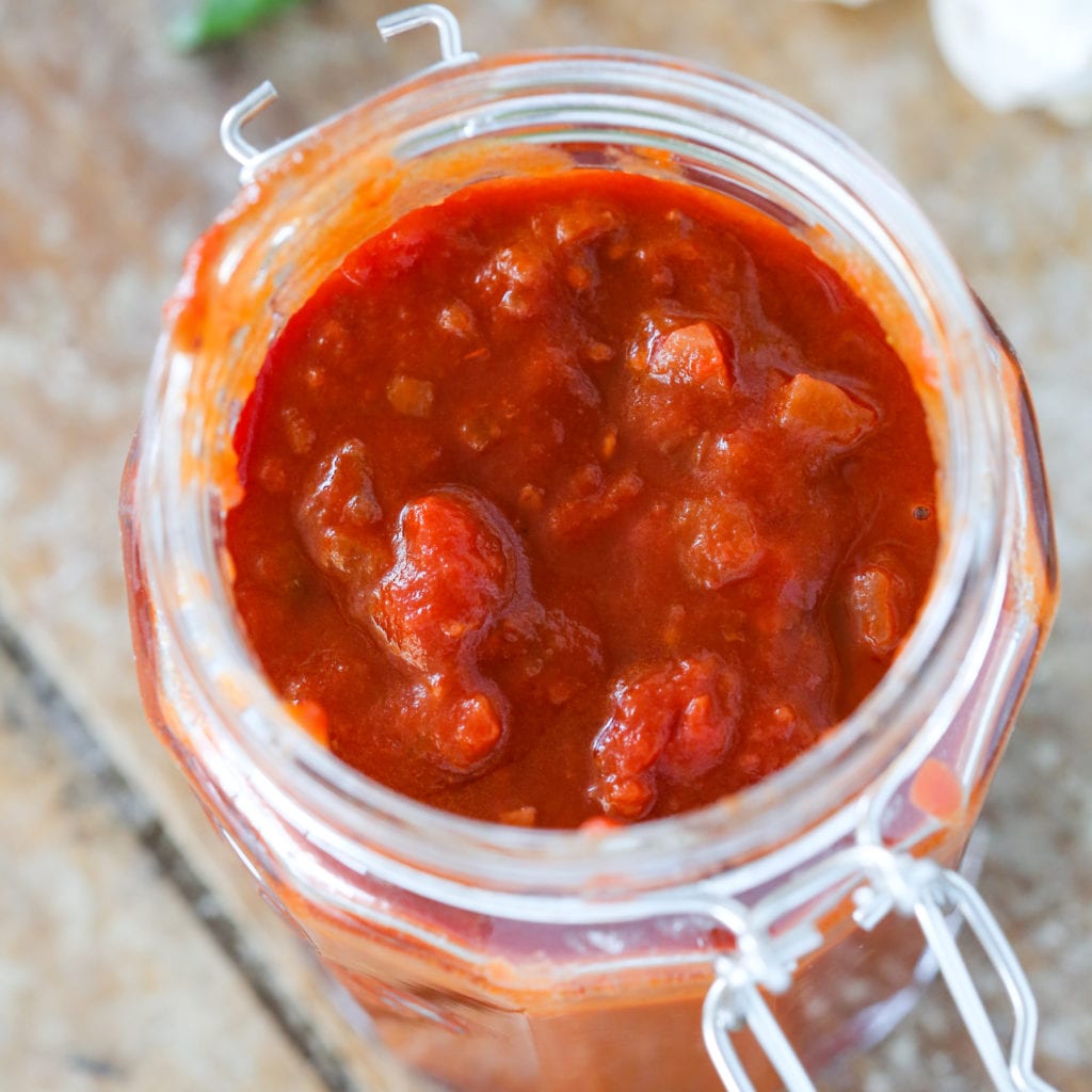 Red wine pasta sauce inside of a mason jar on a wood slate background.