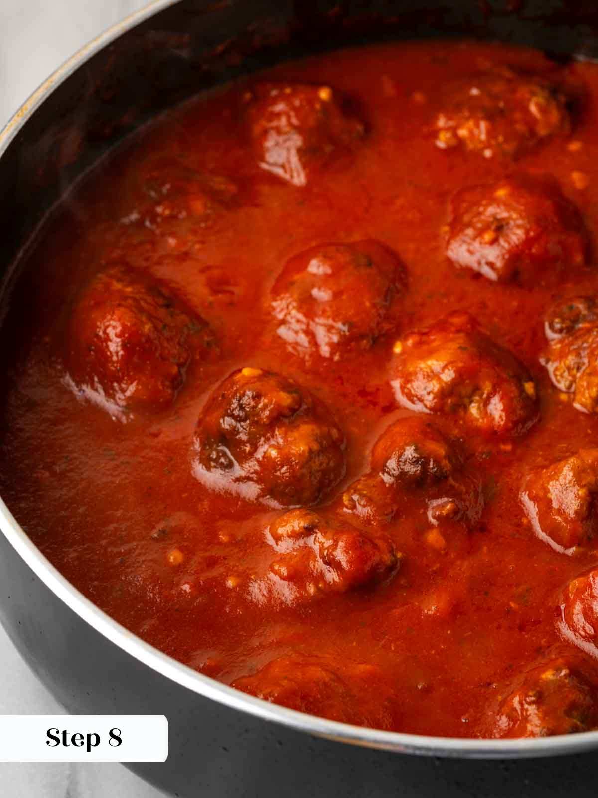 meatballs cooking in red sauce.