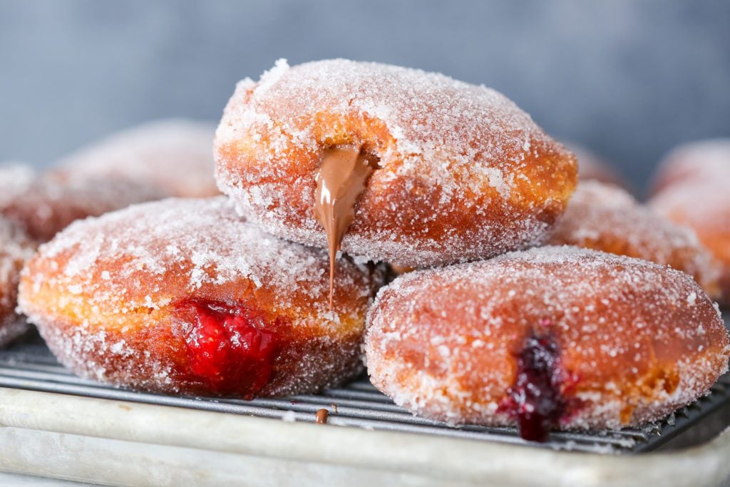 three stuffed donuts stacked on cooling rack.