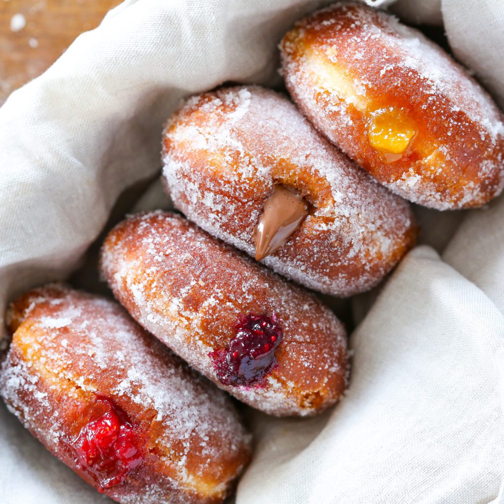four donuts rolled in sugar with fillings.