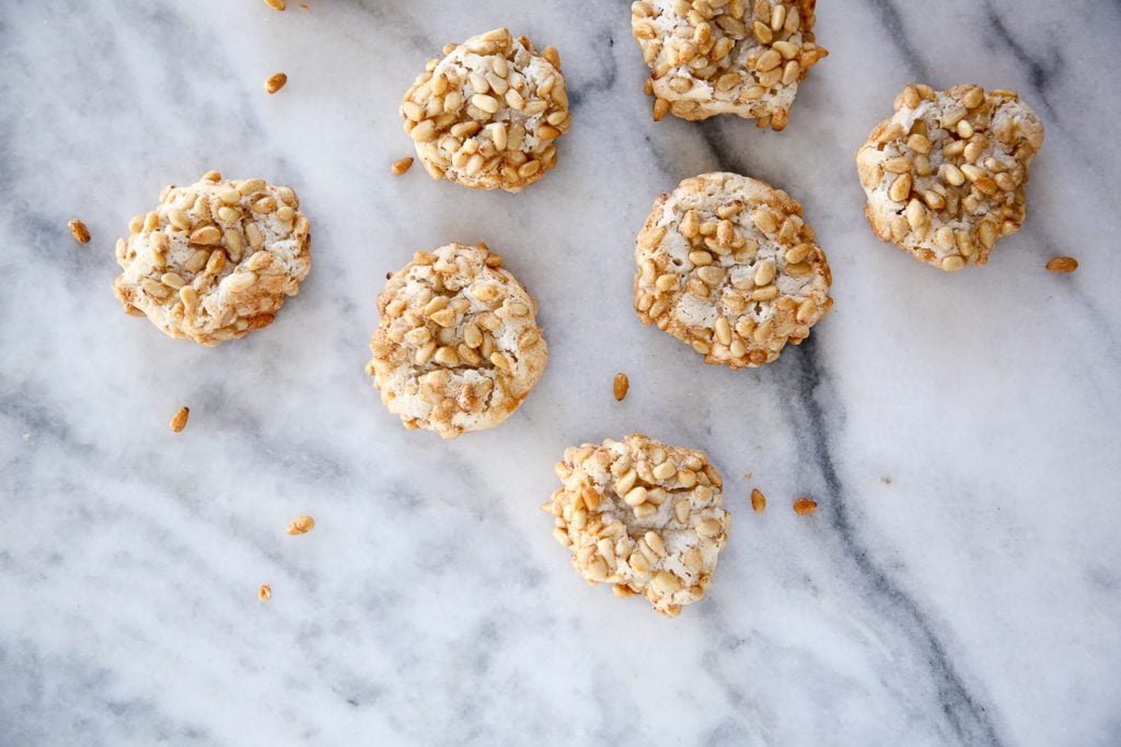 PIgnoli cookies on a white marble countertop.