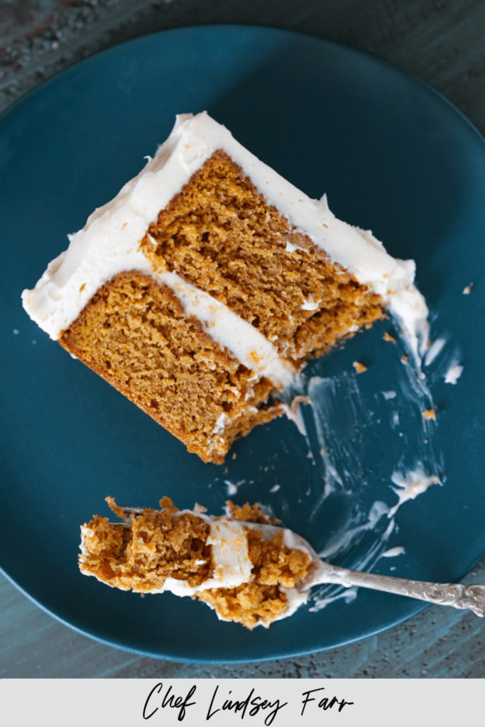 Pumpkin Spice Layer Cake with Cinnamon Cream Cheese Frosting served on a blue plate with silver fork.