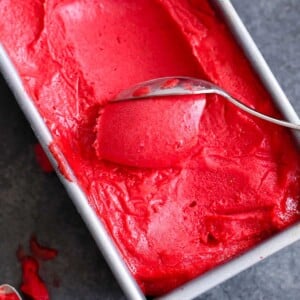 Raspberry Sorbet being scooped with a silver spoon.