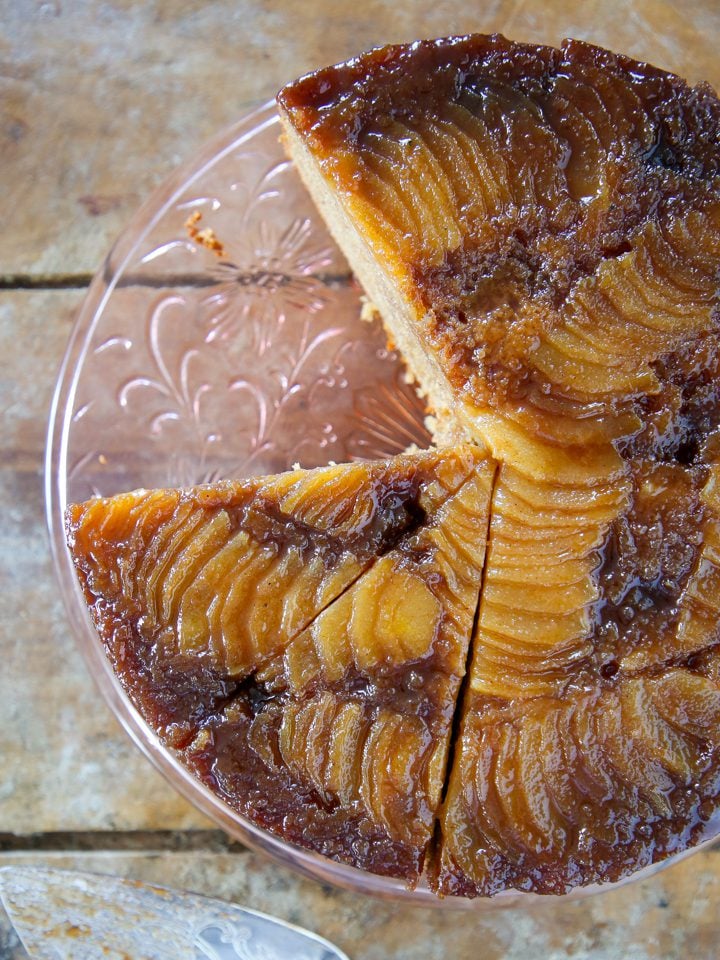 Pear upside down cake on clear cake stand.