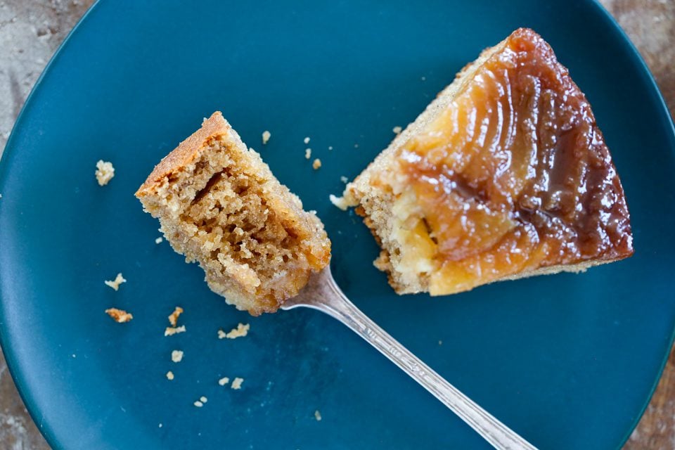 Pear upside down cake slice on a blue plate.